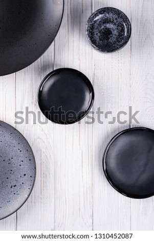 Set of porcelain handcraft  grey and black plates and  bowls on a white wooden table. Flat lay