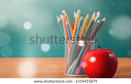 Colorful pencils in jar and red apple