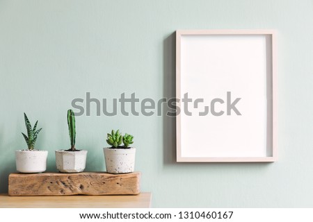 Elegant home interior with mock up frame on the brown table with composition of cacti and succulents on the wooden piece in hipster cement pots. Mint walls. Stylish and floral concept of home garden.
