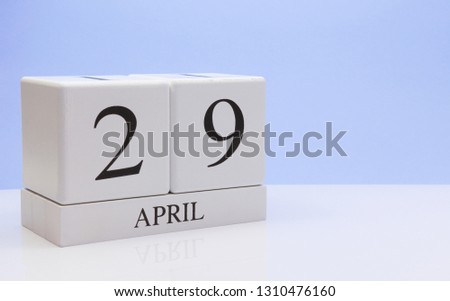 April 29st. Day 29 of month, daily calendar on white table with reflection, with light blue background. Spring time, empty space for text