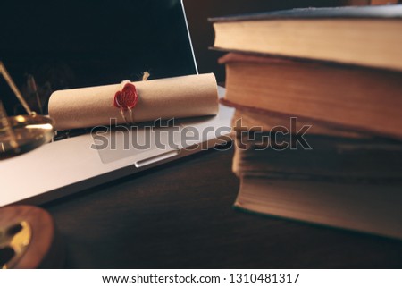 Book stack and laptop computer on workplace in library room with blurred bookshelf background, education concept
