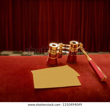 Vintage opera glasses and blank tickets at background of drop-curtain in theatre