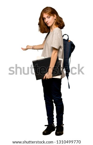 A full-length shot of a Young redhead student pointing back and presenting a product over isolated white background
