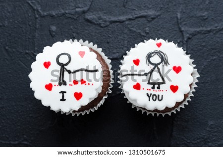 Delicious cupcakes with cute images for Valentine Day on black background. Romantic love background. Happy Valentines Day. Copy space. Top view.