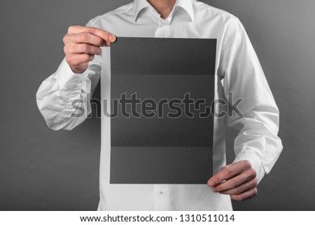 A man in a white shirt holding a black booklet