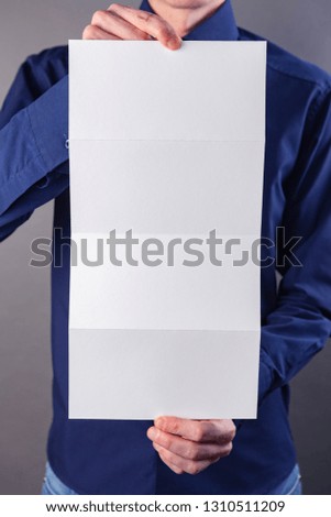 A man in a blue shirt holding a white booklet