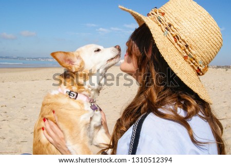 Young girl kissing her little dog on the beach