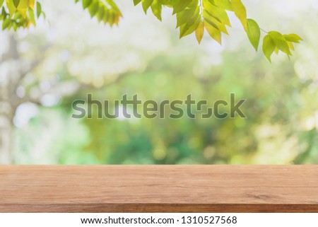 Empty wood table top and blurred view from green tree garden bokeh background - can used for display or montage your products.