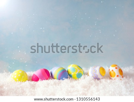 Colorful Happy Easter Eggs in Snow against Blue Sky with sunlight with room or space for copy, text, or your words.  Horizontal with side view