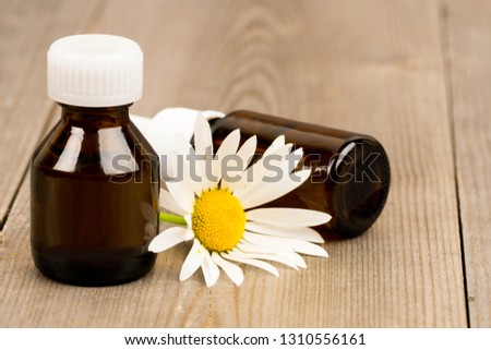 camomile flower and essential oil in brown glass bottles on wooden rustic table