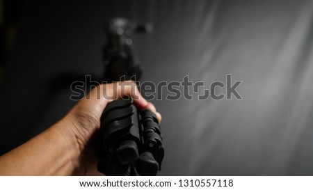 The person holding tripod leg locks, leg locks, tripod in the blur background