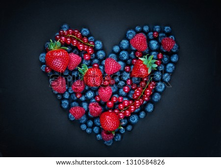 Berry mix fruits in Heart shape on black background.  Assorted berries - Strawberry, Raspberry, Red currant,  Blueberry and Blackberry. Love, Healthy  concept