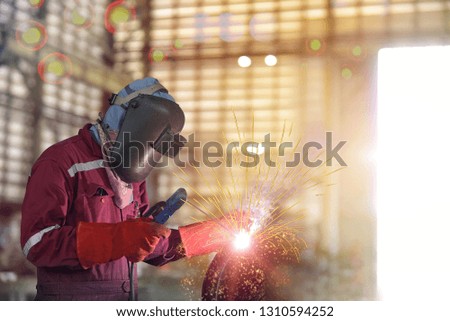 Industrial Worker at the factory welding process close up with protective equipment mask, PPE marks welder on bokeh background.