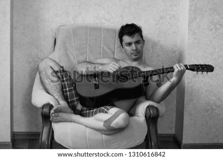 Black and white portrait of a man with a tattoo. Man playing guitar.