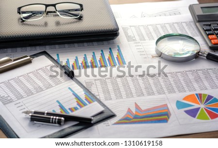 Financial documents - graphics, statistics, drawings, keyboard, laptop, magnifying glass in the office. Business, science, long hours of work. Royalty-Free Stock Photo #1310619158