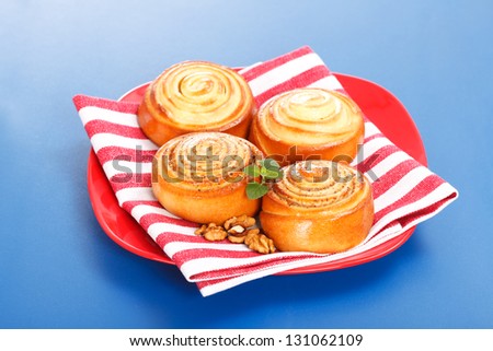 Four cinnamon rolls on red plate, blue background