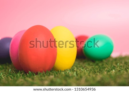 Colorful Easter eggs clean on grass and pink background, easter day concept