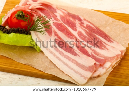 Raw bacon served dill over the wooden background