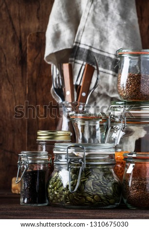 Stocks or set of cereals, pasta, groats, organic legumes and useful seeds in glass jars. Vegan source of protein and energy resources. Healthy vegetarian food. Domestic life scene. Selective focus