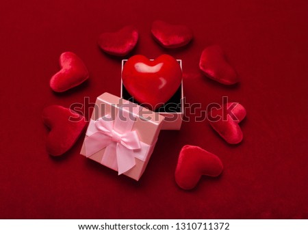 Gift or present box with red bow ribbon and glitter heart on red background for Valentines day