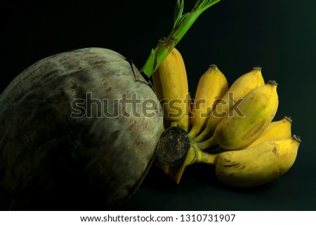 Thai banana and orange and coconut on the timber on black background for art decoration.