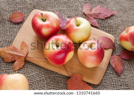 apples on a cutting Board on a burlap with dry autumn leaves