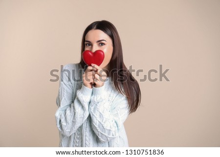 Portrait of young woman with decorative red heart on color background. Space for text