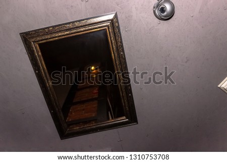 decorative mirror in a vintage frame on the ceiling, which reflects part of the brick column in a metal frame
