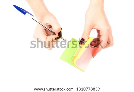 Female hand holding a pen while writing on a notepad against a white background