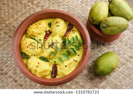 Traditional yellow mango curry or Mampazha Pulissery sweet and sour dish Kerala India . Made from organic raw green mango, coconut milk, seasoned with curry leaves, mustard, Indian red Kashmir chilli.