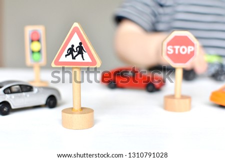 School warning sign, toy cars, road signs, boy playing on the table.