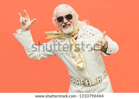 Old dressed up man pensioner who loves rock'n'roll, dancing and having fun on a living coral background - Concept of enjoying life at every age Royalty-Free Stock Photo #1310796464