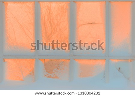 Vintage type old window with snow scene inside in the background tree branch reflection at sunset