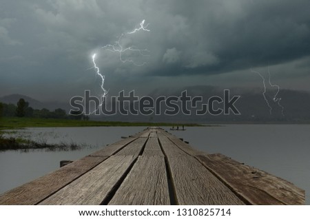 Strong lightning in black clouds over the lake