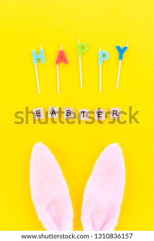 Creative Top view flat lay holiday composition Easter bunny ears eggs text message on bold yellow paper background, copy space. Template Easter day seasonal minimal concept