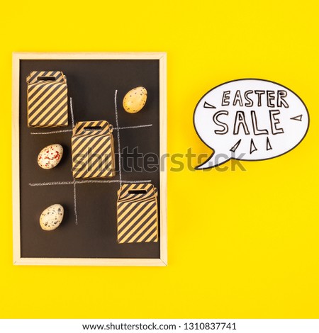 Creative Top view flat lay holiday promo composition Easter sale bunny ears gift boxes eggs text message on bold yellow paper background, copy space. Template Easter day seasonal minimal concept.
