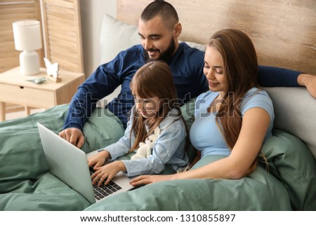 Happy family with laptop on bed at home