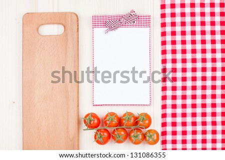 Recipe cookbook, cherry tomatoes, checkered tablecloth, plank on wood background
