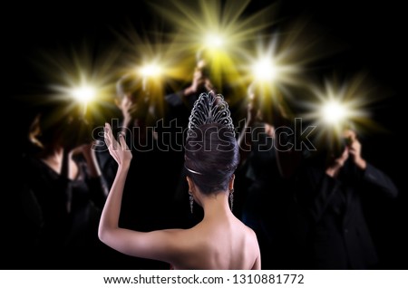 Back side view of Miss Pageant beauty contest with Silver Diamond Crown wave hand to many Photographers who shoot photo image to celebrity at red carpet event, and flash fire light came out copy space