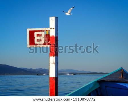 Mile marker post on Lake Inle in Myanmar (Burma) with seagull flying over