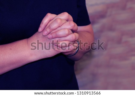 A woman is holding hands for praying to the Lord at Church in Thailand.
