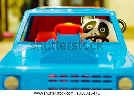 Toy plastic panda driving a blue SUV