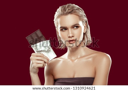 Posing with chocolate. Dark-eyed young model having strong face while posing with chocolate