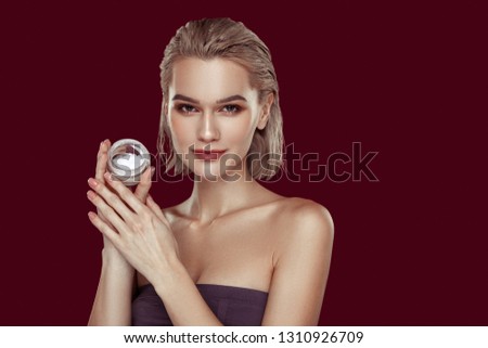 Pack of cream. Slim appealing professional model holding little pack of cream standing near wall