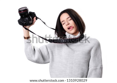 Attractive brunette aims her camera. composing a photograph in studio, isolated on white