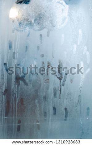 A cloud with rain drops is drawn on the sweaty foggy window. Water droplets condensation background of dew on glass. Be happy even in bad rainy weather outside concept.