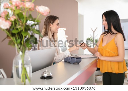 Young woman booking room in hotel at reception