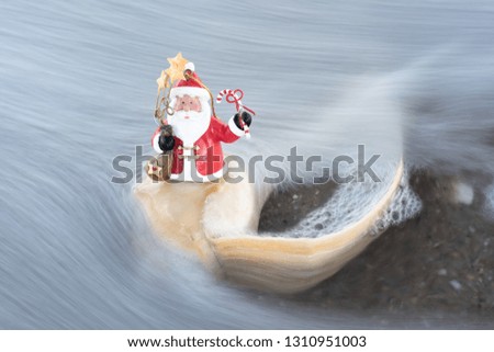 Coastal holiday background of Santa riding on an incoming seashell pushed onto the beach by an ocean wave.