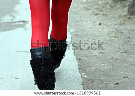 Legs of a girl in red tights and black boots