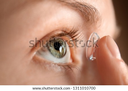 Young woman putting lens in her eye, closeup Royalty-Free Stock Photo #1311010700
